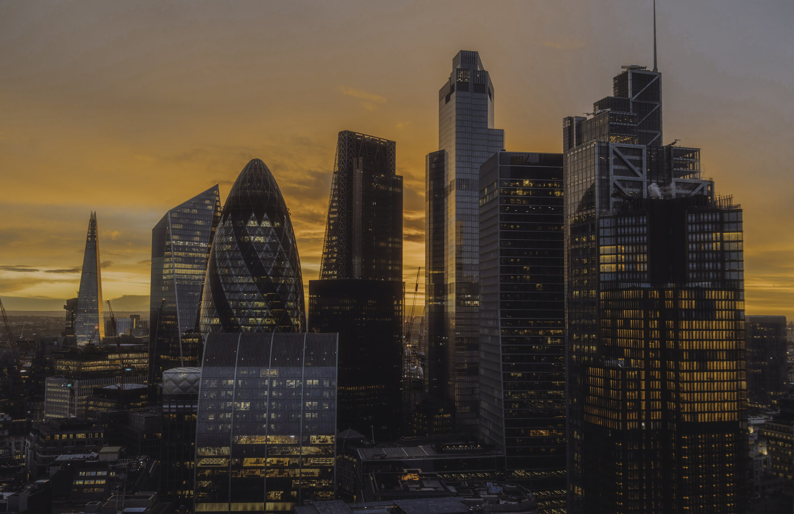 An enchanting scene of London’s financial district at golden hour, showcasing iconic landmarks like the Gherkin and the Shard against a vibrant sunrise. The warm hues of the rising sun illuminate the sleek glass and steel architecture, blending natural beauty with urban sophistication. This image perfectly encapsulates the dynamic energy and elegance of London's cityscape during a tranquil morning